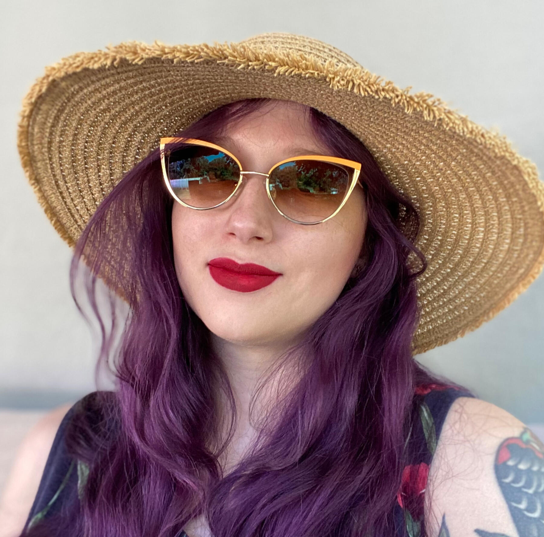 Photo of Liz, wearing sunglasses and a sun hat.